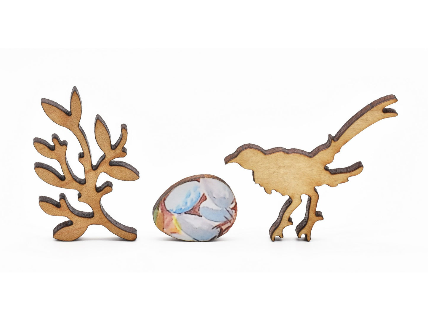 A closeup of pieces in the shape of a branch, an egg, and a bird.