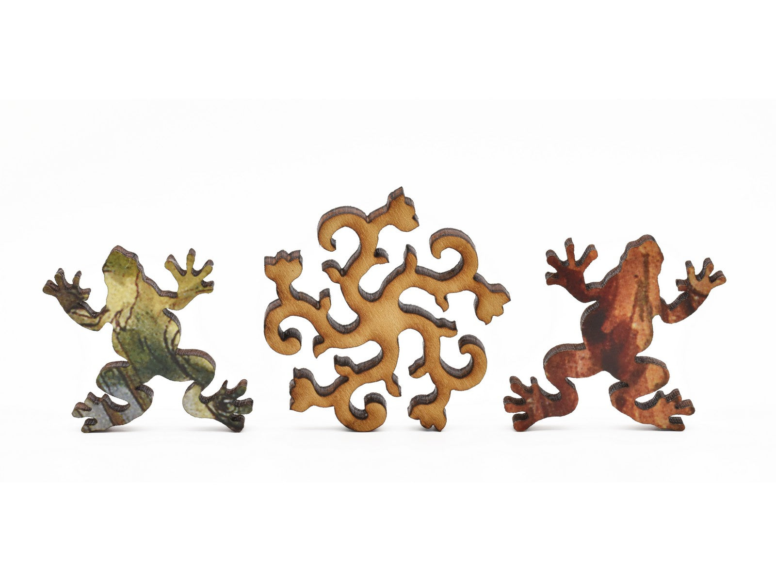 A closeup of pieces in the shape of flowering vines and frogs.