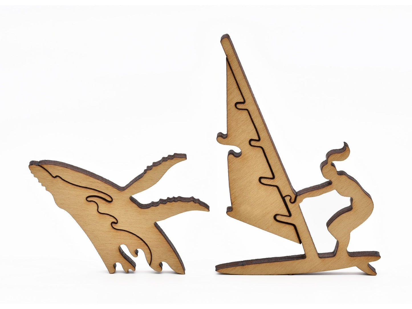 A closeup of pieces in the shape of a whale and a wind surfer.