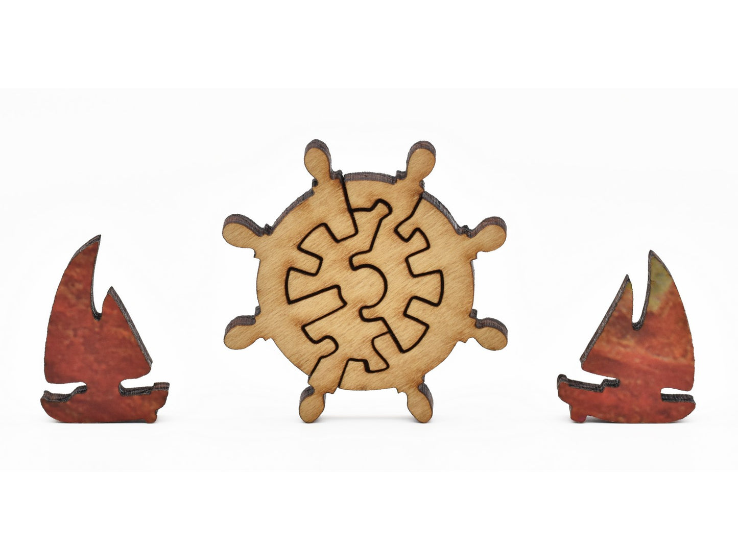 A closeup of pieces in the shape of a helm wheel and sailboats.