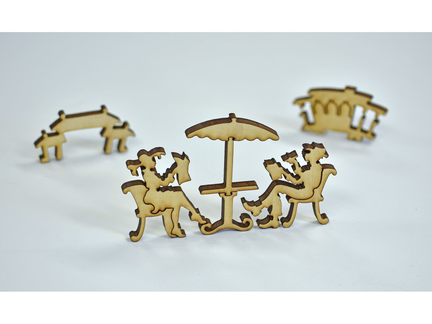 A closeup of pieces in the shape of two people sitting at a cafe table.