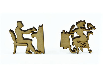 A closeup of pieces in the shape of two people sitting at desks.