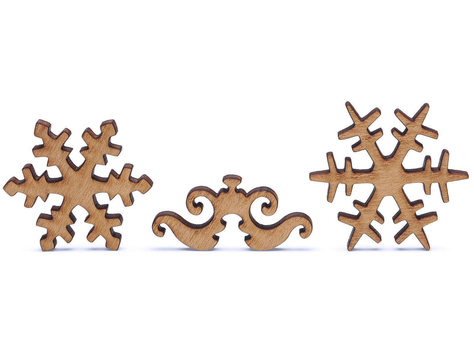 A closeup of pieces shaped like two snowflakes and an ornament.