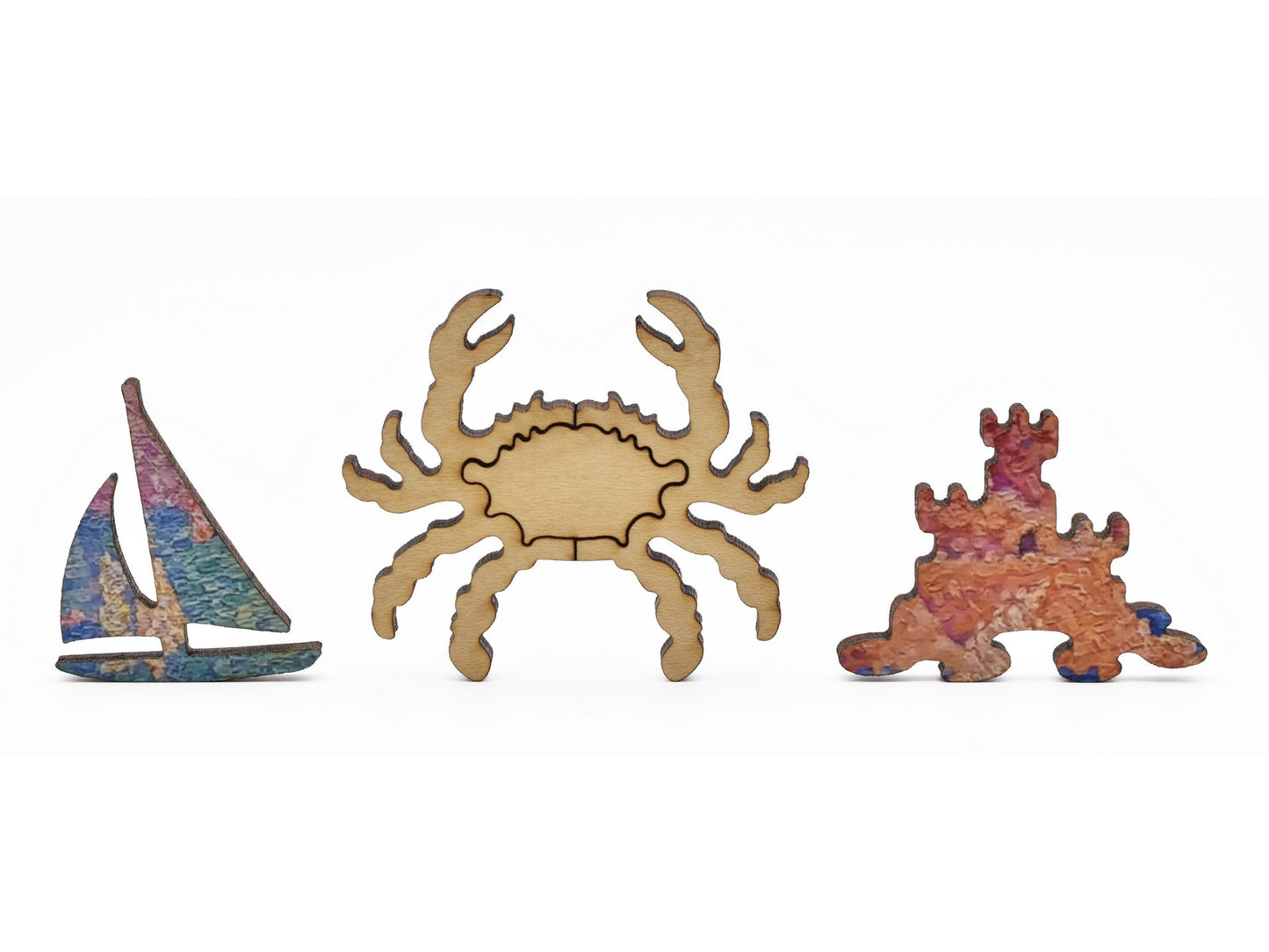 A closeup of pieces in the shape of a sailboat, a crab, and a sandcastle.