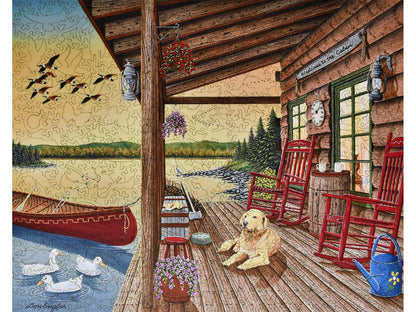 The front of the puzzle, Welcome to the Cabin, with a dog on a porch by a lake.