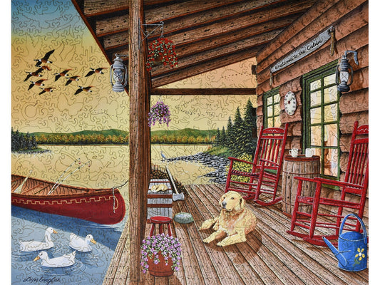 The front of the puzzle, Welcome to the Cabin, with a dog on a porch by a lake.