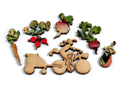 A closeup of whimsy pieces, picturing a woman on a bicycle, and assorted vegetables. 