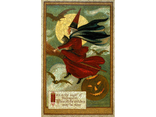 The front of the puzzle, The Night of Halloween, which shows a witch riding a broomstick with a cat in the night sky with the moon and bats behind her.