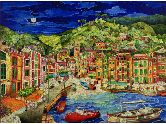 The front of the puzzle, Portofino, Italy, picturing a night scene in a coastal town, boats on the ocean, and colorful houses.