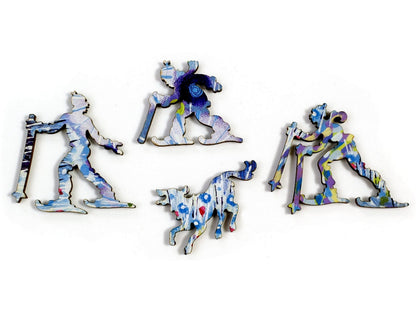 A closeup of pieces in the shape of three skiers and a dog.